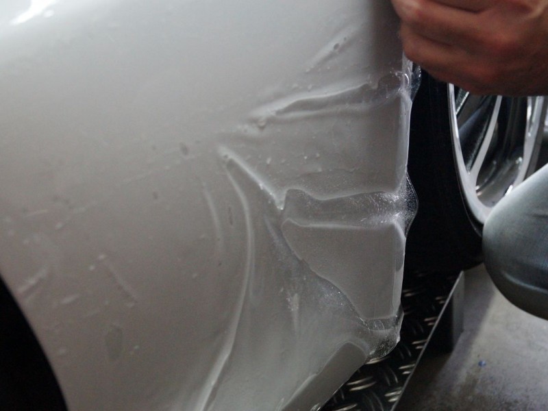 Montage einer transparenten Steinschlagschutzfolie an einem weißen Porsche Boxter GTS