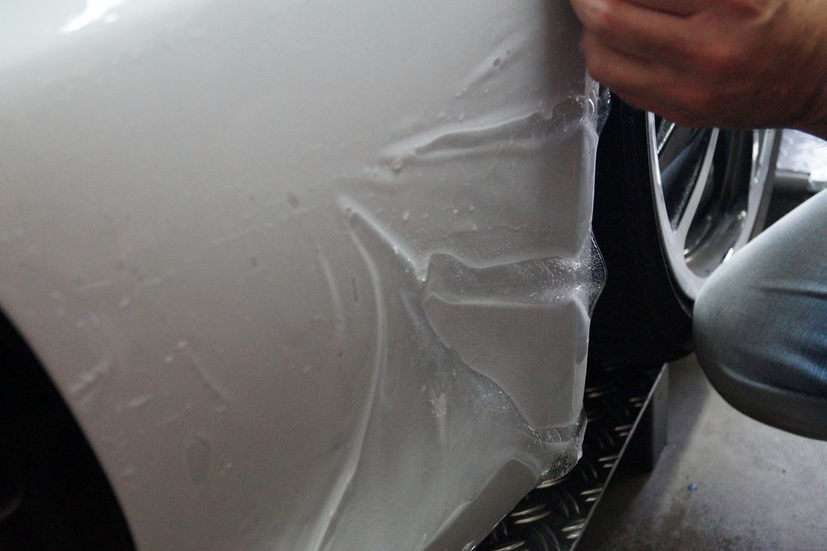 Montage einer transparenten Steinschlagschutzfolie an einem weißen Porsche Boxter GTS