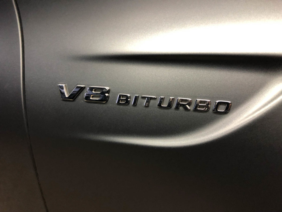 Exakter Zuschnitt der Steinschlagschutzfolie um das V8 BiTurbo Emblem - Mercedes Folierung by Sticker-Werk